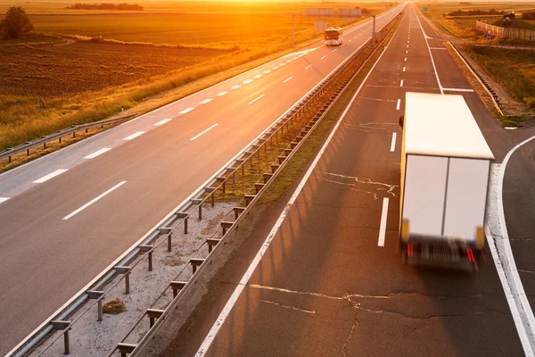 Camion e autobus in moto blur al tramonto — Stockfoto