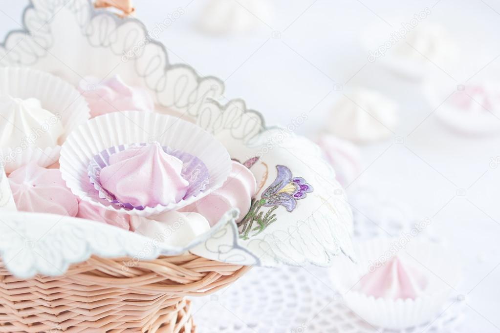 Pink and white meringue cookies in a basket. Selective focus