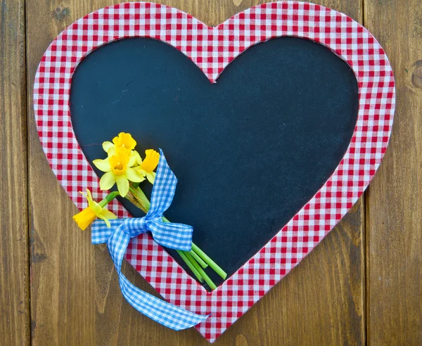 Heart-shaped chalkboard and fresh daffodils — Stock Photo, Image