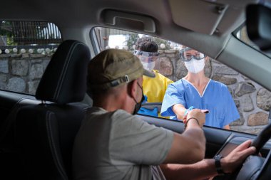 Araba sürücüsü, pasaportunda koronavirüs aşısı olduğunu gösteriyor.