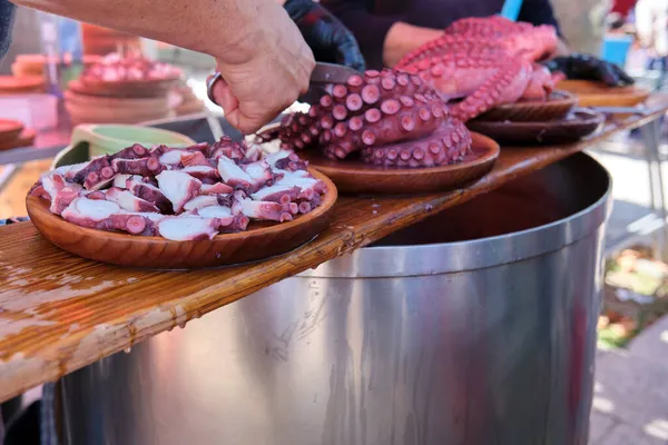 Tanınmayan adam, geleneksel Galiçya ahtapot tarifi olan yemeğin bir kısmını hazırlıyor..