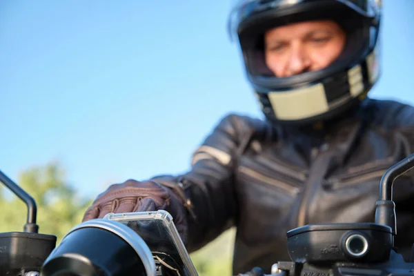 Мотоцикліст поза фокусом, використовуючи смартфон на мотоциклі — стокове фото