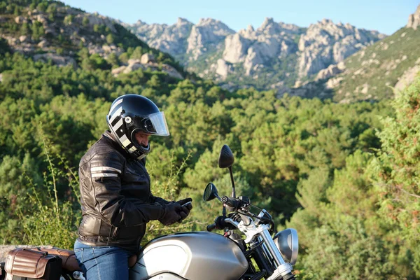Pengendara sepeda motor menggunakan ponsel di alam — Stok Foto