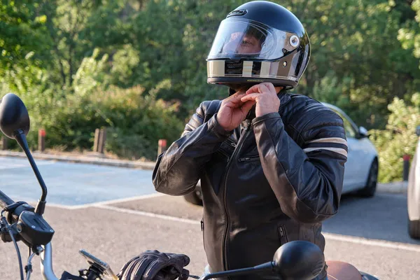 Motosiklete binmeden önce bir motorcu kask takar.