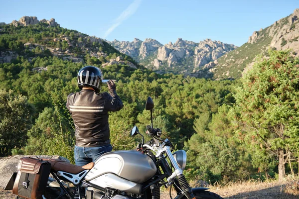 Seorang pria mengendarai sepeda motor mengambil foto dengan smartphone di alam. — Stok Foto
