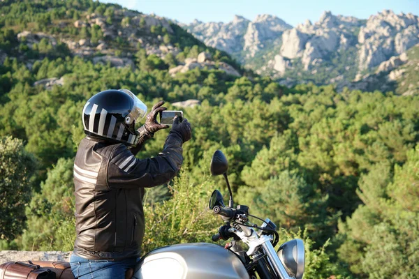 Pengendara sepeda motor mengambil gambar dengan smartphone di alam. — Stok Foto
