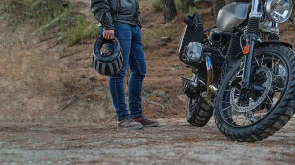 Нерозпізнана людина з шоломом в руці, що стоїть поруч з припаркованим мотоциклом — стокове фото