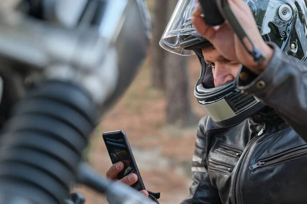Занепокоєний мотоцикліст викликає страхування мотоциклів зі своїм мобільним телефоном — стокове фото
