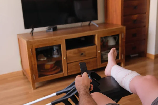 テレビを見ながら遠隔操作で脚を負傷した熟女 — ストック写真