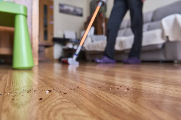 A unrecognizable woman out of focus vacuuming. Focus on the dirt