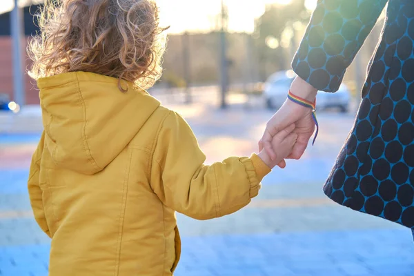 Mother walking hand in hand with her young son enjoying a moment of family togetherness in a park at sunset. — Zdjęcie stockowe