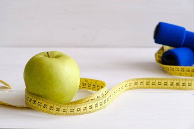 Apple, tape measure and dumbbells, diet concept