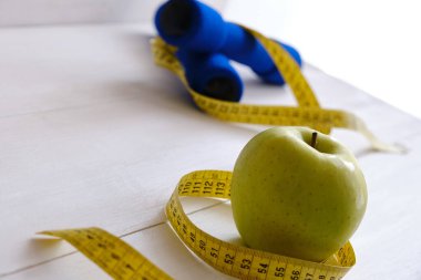 Dambıllar, taze elma ve mezura, diyet ve egzersiz kavramı.