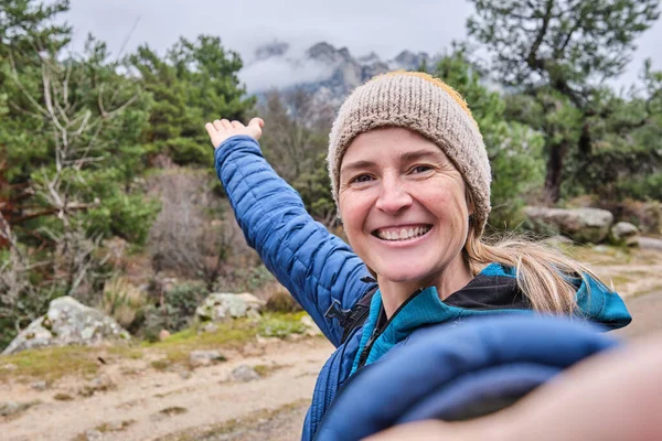 Szczęśliwa piękna kobieta robi portret selfie ze smartfonem na górze zimą. — Zdjęcie stockowe