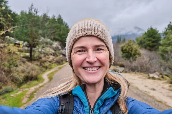 Szczęśliwa kobieta robi selfie portret ze smartfonem na łonie natury w zimie. — Zdjęcie stockowe