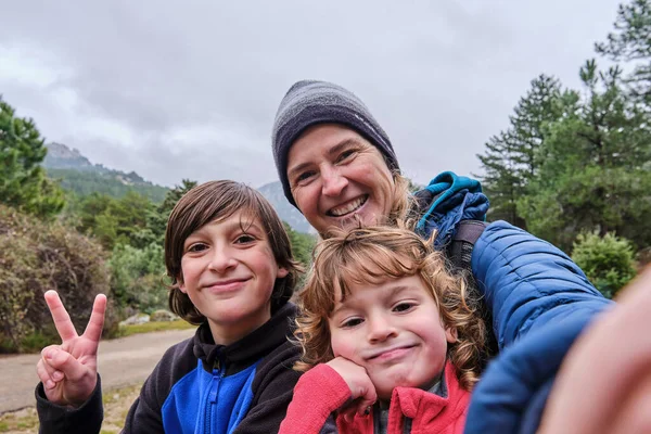 Una familia feliz tomando un retrato selfie con smartphone en las montañas en invierno — Foto de Stock