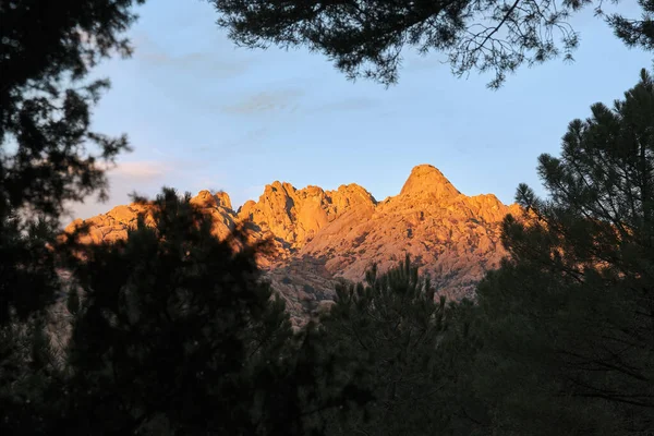El Yelmo, toppen av La Pedriza sett utifrån skogen vid solnedgången. — Stockfoto