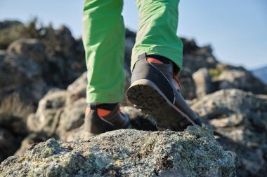 Sırt çantalı tanınmayan bir çocuk doğada kayalara tırmanıyor.