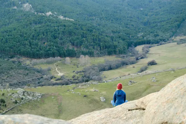 En kvinna i hatt och jacka mediterar på berg — Stockfoto