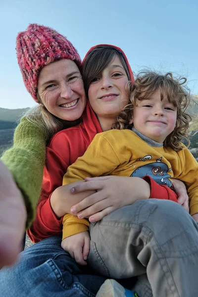 Una madre feliz haciendo una selfie con sus hijos en la naturaleza — Foto de Stock