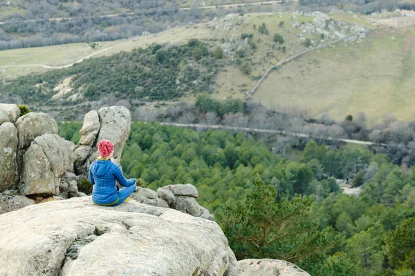 Una mujer sentada en el borde del acantilado de la montaña. — Foto de Stock