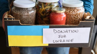 Ukraynalı mülteciler için yiyecek dolu bir kutu tutan tanınmayan bir adam..