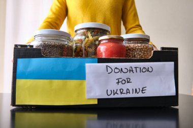 Tanınmayan bir kadın Ukraynalı mültecilere bağışlamak için bir kutu yiyecek alıyor..