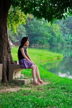 sevimli Tay kız nehir kıyısında kendisi ile gülüyor