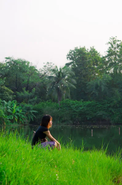 Schattig Thaise meisje is laat haar gedachten stroom over de rivier bank — Stockfoto