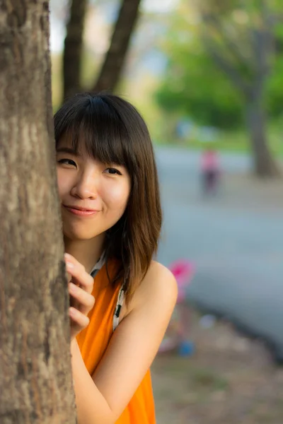 Menina tailandesa bonito escondido atrás da árvore — Fotografia de Stock