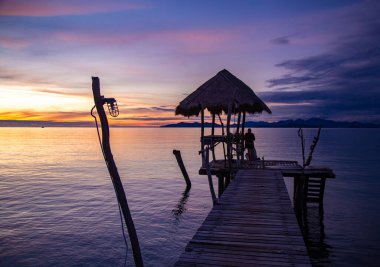 Denizde ahşap plaj barının üzerinde gün batımı ve Koh Mak adasında bir kulübe, Trat, Tayland