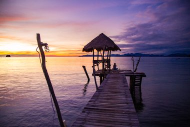 Denizde ahşap plaj barının üzerinde gün batımı ve Koh Mak adasında bir kulübe, Trat, Tayland