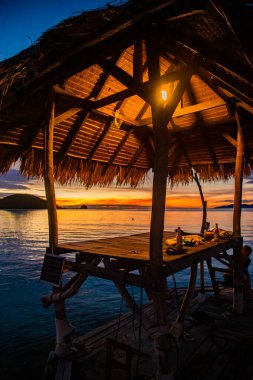 Denizde ahşap plaj barının üzerinde gün batımı ve Koh Mak adasında bir kulübe, Trat, Tayland