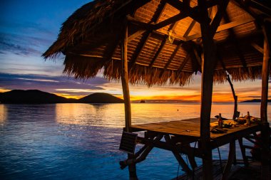 Denizde ahşap plaj barının üzerinde gün batımı ve Koh Mak adasında bir kulübe, Trat, Tayland