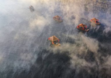 Ban Rak Thai 'de, Tayland' da Mae Hong Son 'da bir göl kenarındaki Çin köyünün üzerinde sisli gündoğumu manzarası.