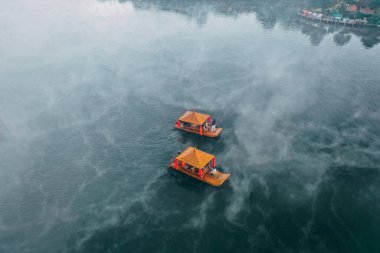 Ban Rak Thai 'de, Tayland' da Mae Hong Son 'da bir göl kenarındaki Çin köyünün üzerinde sisli gündoğumu manzarası.