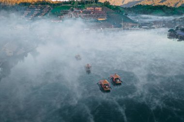 Ban Rak Thai 'de, Tayland' da Mae Hong Son 'da bir göl kenarındaki Çin köyünün üzerinde sisli gündoğumu manzarası.