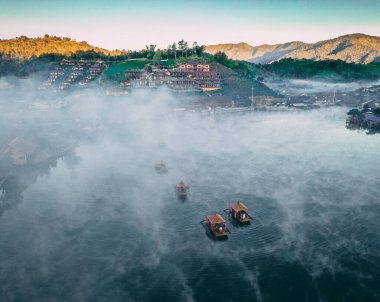 Ban Rak Thai 'de, Tayland' da Mae Hong Son 'da bir göl kenarındaki Çin köyünün üzerinde sisli gündoğumu manzarası.