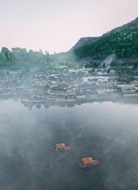 Ban Rak Thai 'de, Tayland' da Mae Hong Son 'da bir göl kenarındaki Çin köyünün üzerinde sisli gündoğumu manzarası.