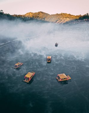 Ban Rak Thai 'de, Tayland' da Mae Hong Son 'da bir göl kenarındaki Çin köyünün üzerinde sisli gündoğumu manzarası.