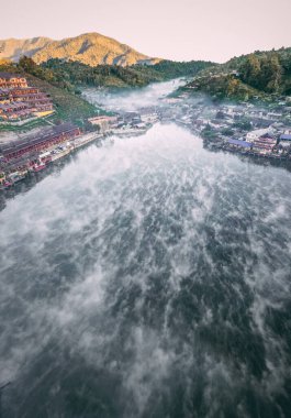 Ban Rak Thai 'de, Tayland' da Mae Hong Son 'da bir göl kenarındaki Çin köyünün üzerinde sisli gündoğumu manzarası.