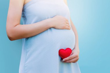 Mavi arka planda mavi elbiseli hamile bir kadın. Hamilelik, ebeveynlik, annelik kavramı. Kopyalama alanı olan çocuk konsepti.