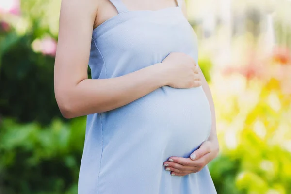 自然を背景に青いドレスを着た妊婦さんがクローズアップ 母親の概念 子供の概念への愛 — ストック写真
