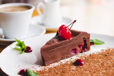 Kirazlı ve naneli çikolatalı kek ile bir fincan kahve. Bir kafede çikolatalı tatlı. Ev yapımı tatlı tarifleri.