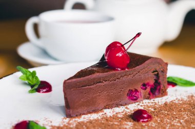Kirazlı ve naneli çikolatalı kek ile bir fincan çay. Bir kafede çikolatalı tatlı. Ev yapımı tatlı tarifleri.