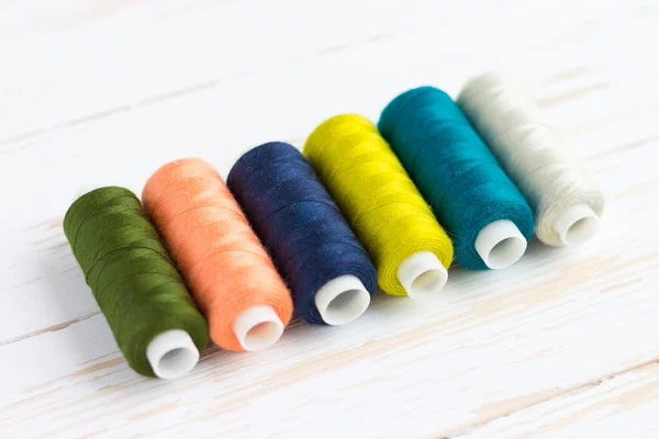 Colourful thread spools on a yellow wooden background