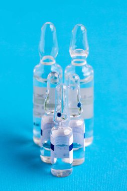 Mavi arka planda tıbbi ampuller var. Mavi arka planda cam tıbbi ampullerle aşı. Tıbbi ampuller