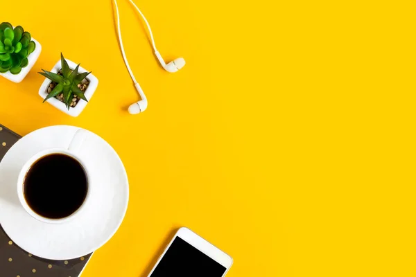 Morning coffee, notebook, mobile phone, plants on a yellow background. Copy space. Top view. Business yellow background. Flat lay, concepts ideas