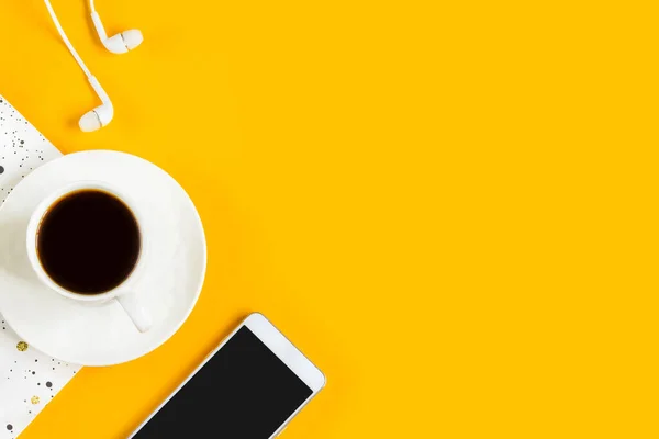 Morning coffee, notebook, mobile phone on a yellow background. Copy space. Top view. Business yellow background. Flat lay, concepts ideas