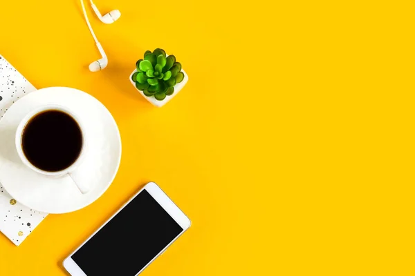 Morning coffee, notebook, mobile phone, plants on a yellow background. Copy space. Top view. Business yellow background. Flat lay, concepts ideas